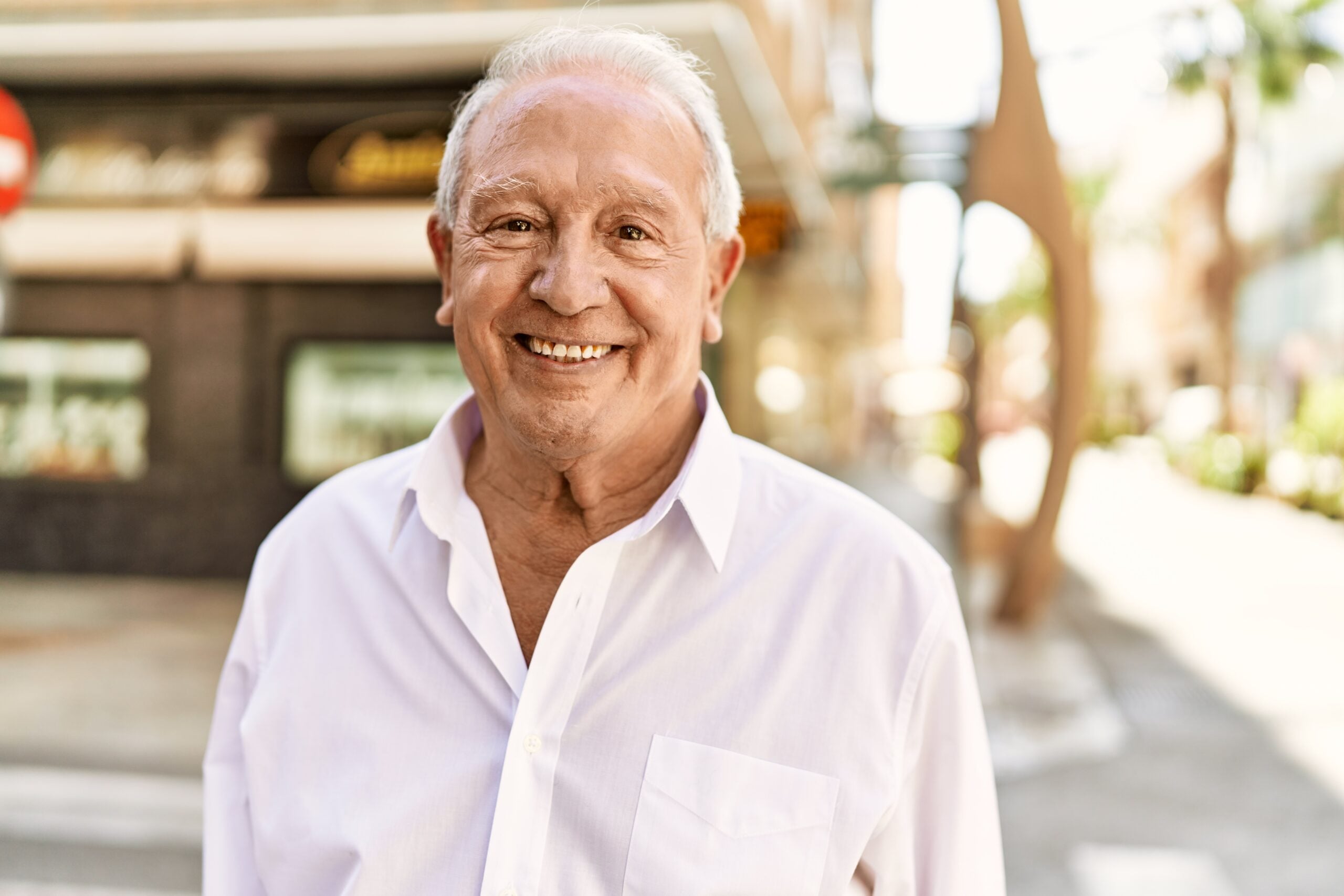 Senior man with grey hair standing happy outdoors on a sunny day. Smiling happy at 70s for retirement